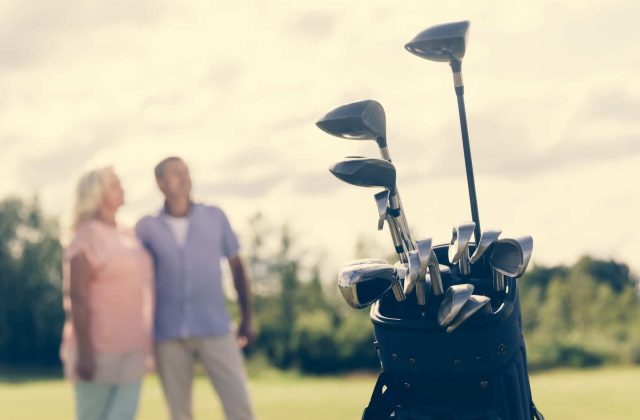 Golf bag standing on a grass field, people in the background