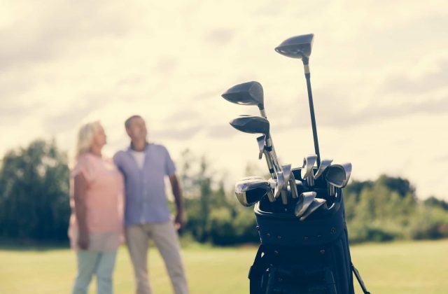 Golf bag standing on a grass field, people in the background