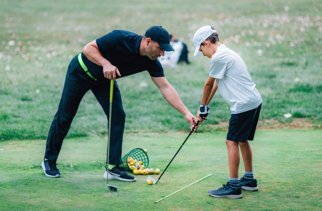 Golf Lessons. A golf Instructor and a boy practicing on a Golf Practice Range
